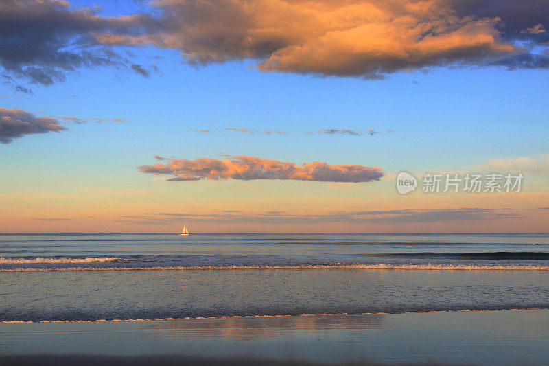 缅因州Ogunquit海滩上的日落，海浪和帆船。