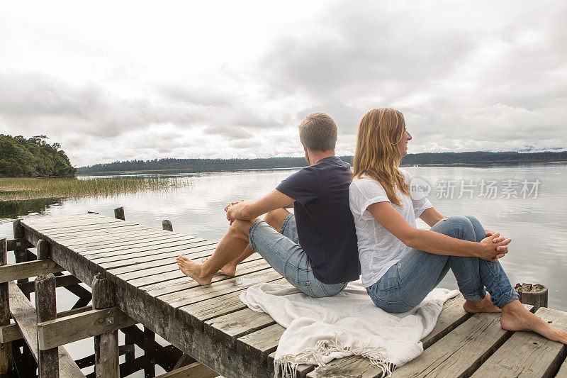 愉快的年轻夫妇在湖边码头上放松
