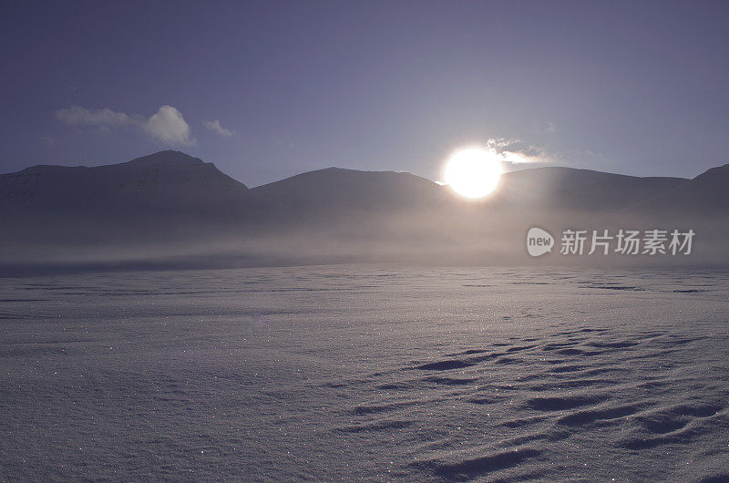 日落在山在广阔的雪“沙漠”低云