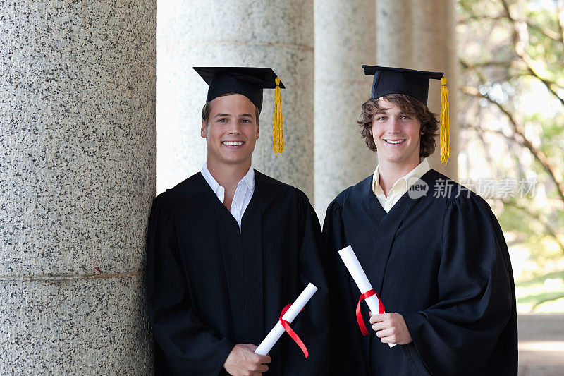 两个毕业生的肖像男性拿着他们的文凭