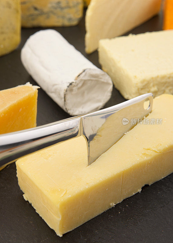 八种不同的英国奶酪和切奶酪刀放在石板上