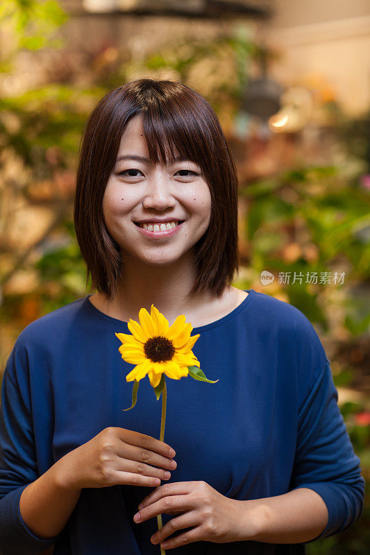 一个女人在花店里拿着向日葵