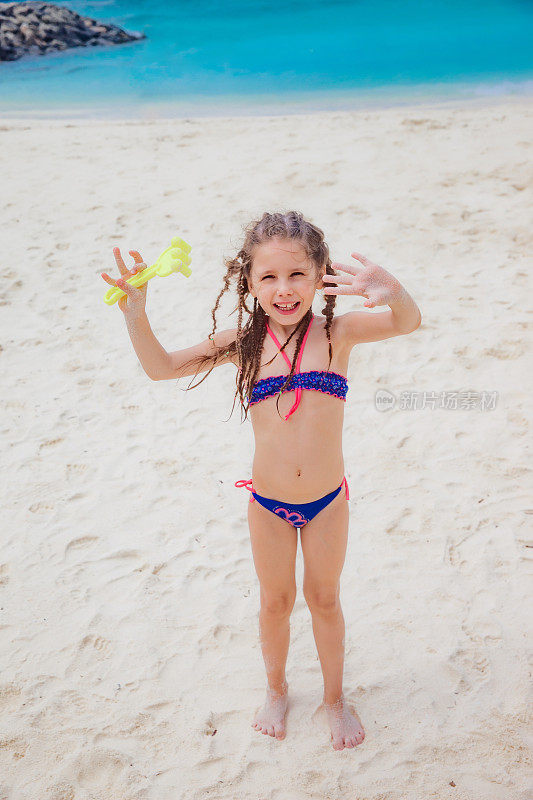 小女孩在热带海滩上建造沙堡