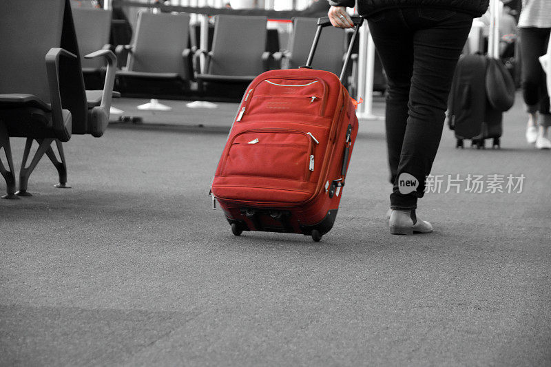带着一个红色行李箱在机场