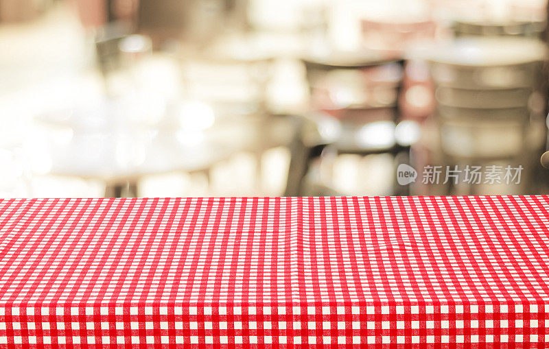 空桌子与红色格子桌布上模糊的咖啡馆与散景背景