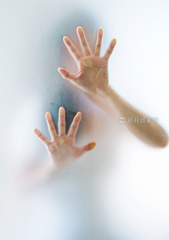 女人的手在磨砂玻璃后面做着恐惧的手势