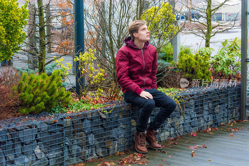 一个少年坐在城市公园里等着