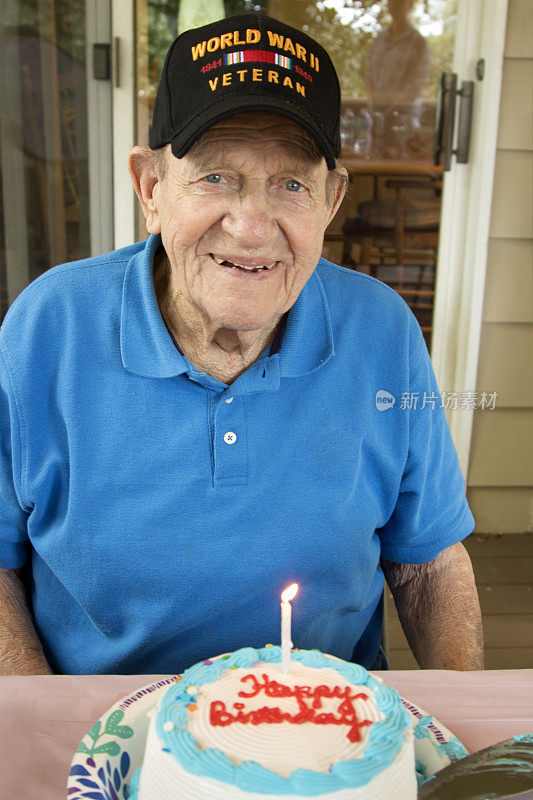 生日快乐，戴着帽子的二战老兵，坐在生日蛋糕和点燃的蜡烛