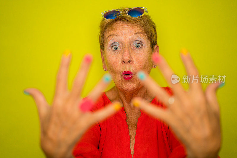 为时尚的老年人的颜色激增-有趣的年长妇女显示她涂指甲