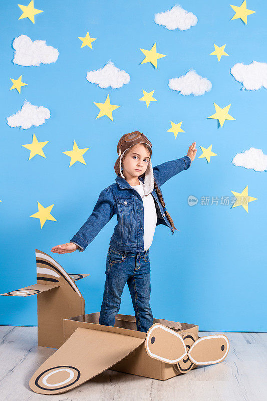 一个穿着飞行员服装的小女孩正在玩，梦想着飞越云层