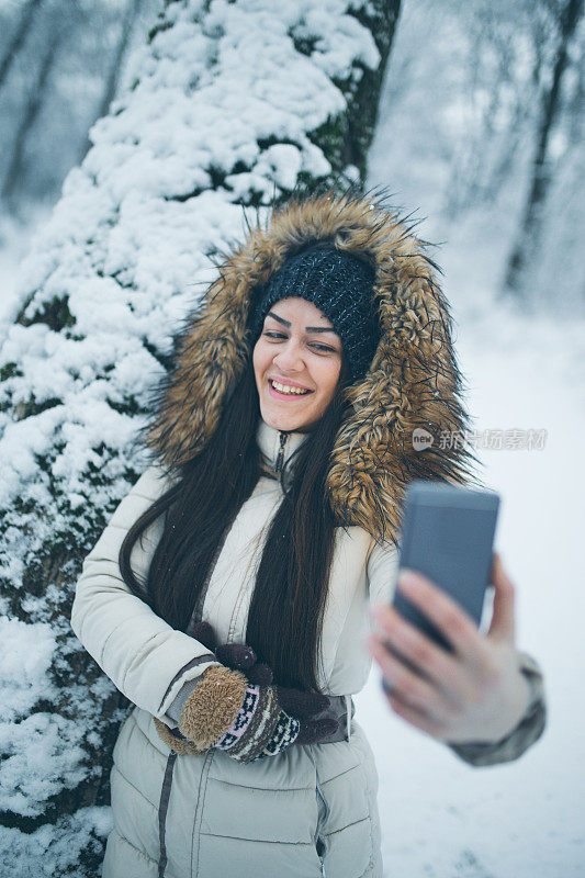 女孩享受冬天，在下雪的时候自拍