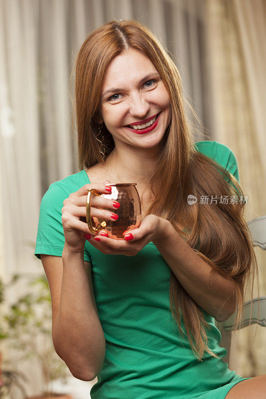 穿绿衣服的女人拿着一个铜杯