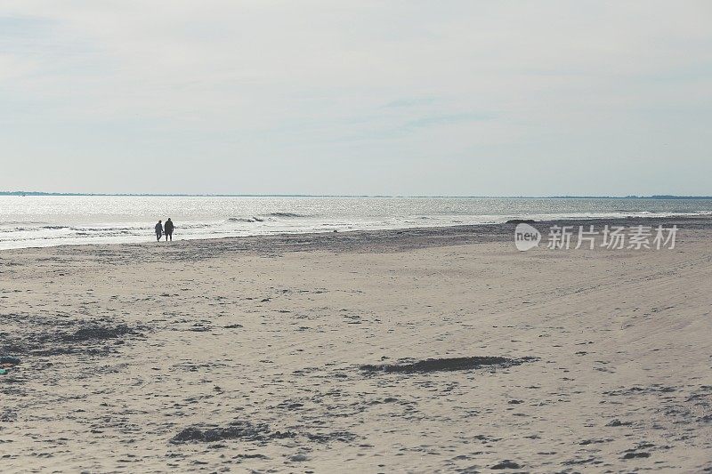 一个人在沙滩上，两个人在沙滩上散步