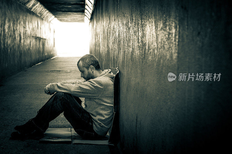 年轻孤独的流浪汉坐在黑暗的地铁隧道里