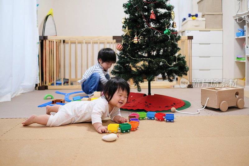 圣诞节时婴儿和蹒跚学步的孩子在客厅玩玩具