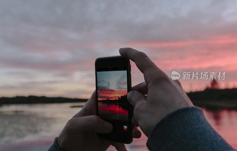 一个男人在湖边拍了一张日落的照片。