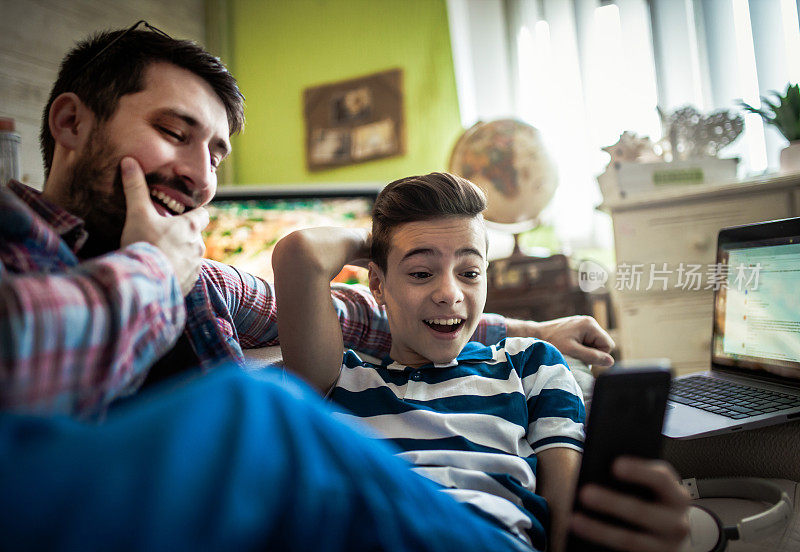 微笑的父子在客厅里使用数码设备