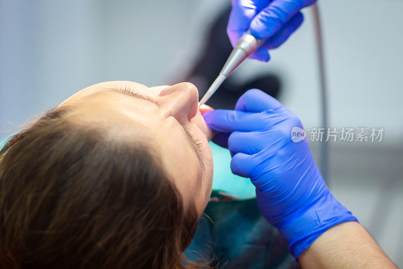 牙科医生在牙科诊所为一位女病人治疗牙齿。