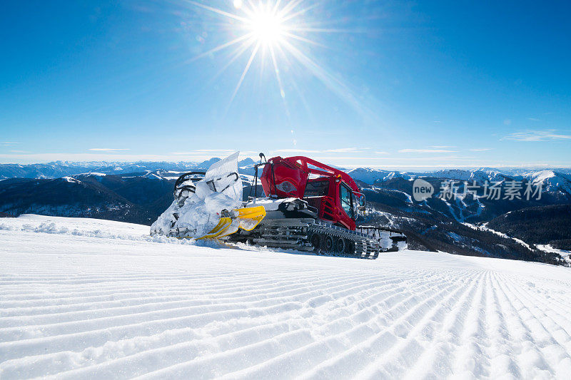 现代的红色雪清理多余的雪从滑雪道，因为太阳照耀明亮