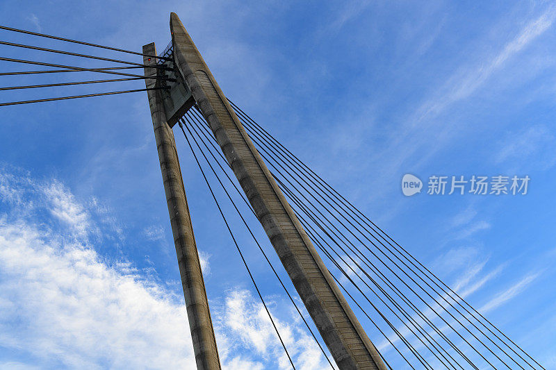 悬索桥的缆柱以蓝天和白云为背景。