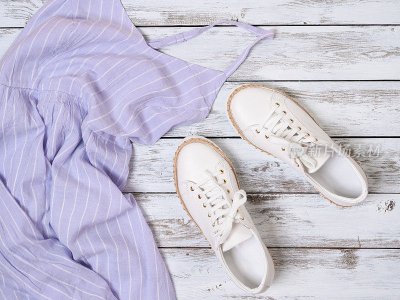 女士服装、鞋子(淡紫色连衣裙、白色皮革运动鞋)。时尚套装，春夏系列。购物的概念。平躺，从上面看