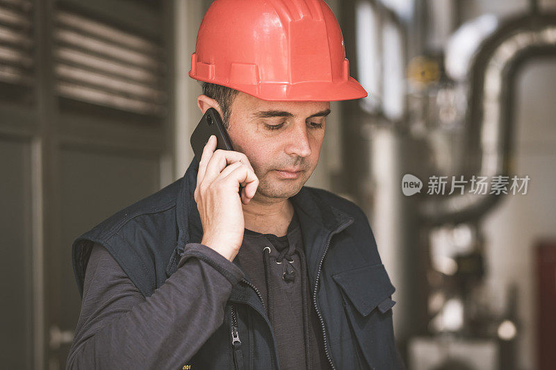 在工厂里使用手机的男性技术员