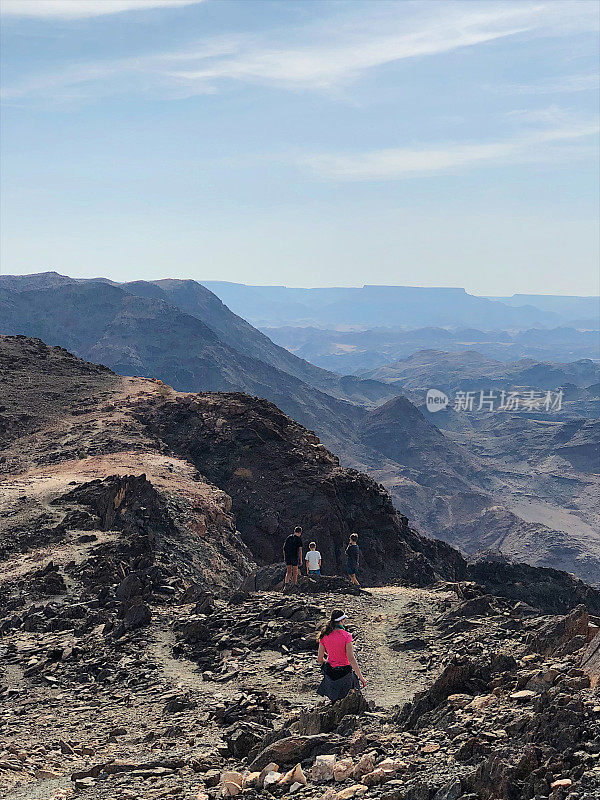 孩子们在贫瘠的山区徒步旅行，山下有河流峡谷