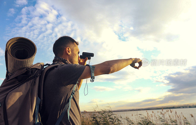 年轻的旅行者用双筒望远镜观察大自然。旅游度假概念