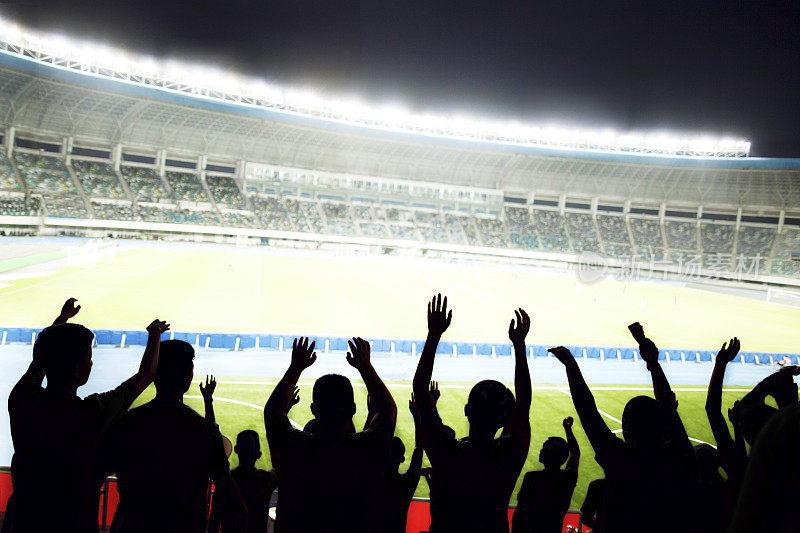 在体育场举行的体育赛事上，热情的球迷欢呼、举手
