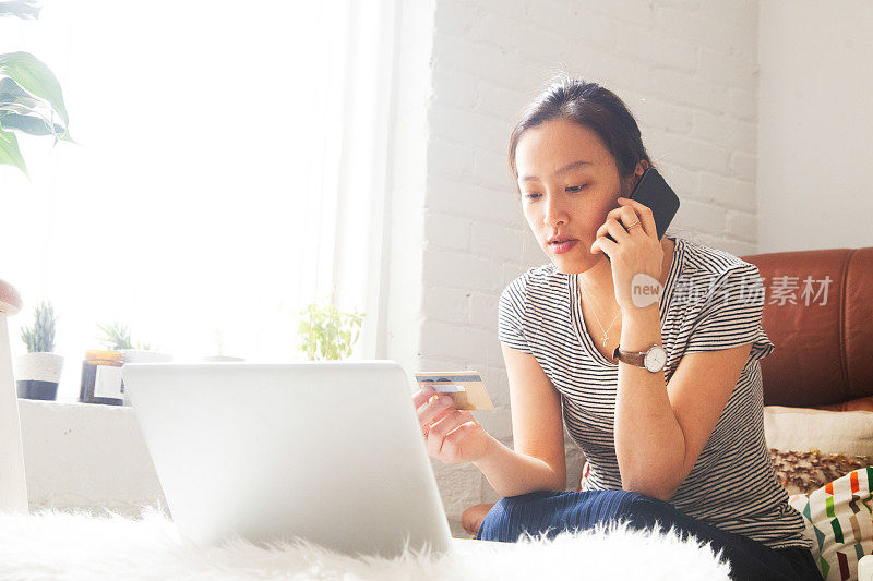 一个年轻的亚洲女人手里拿着信用卡和客服聊天