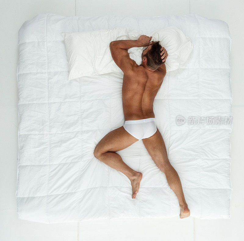 年轻男子穿着泳裤在卧室的白色背景前休息