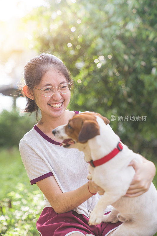 亚洲家庭十几岁的女孩玩好玩的她的宠物杰克罗素梗狗在花园在夏天的早晨