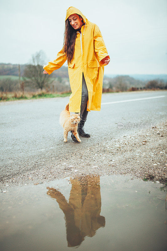 快乐的女孩和猫在大自然的雨