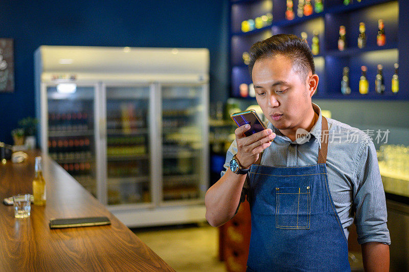 亚洲咖啡师使用语音识别对着手机说话