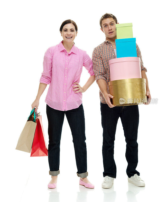 白人女性购物狂穿着裤子，手持礼盒站在白色背景前