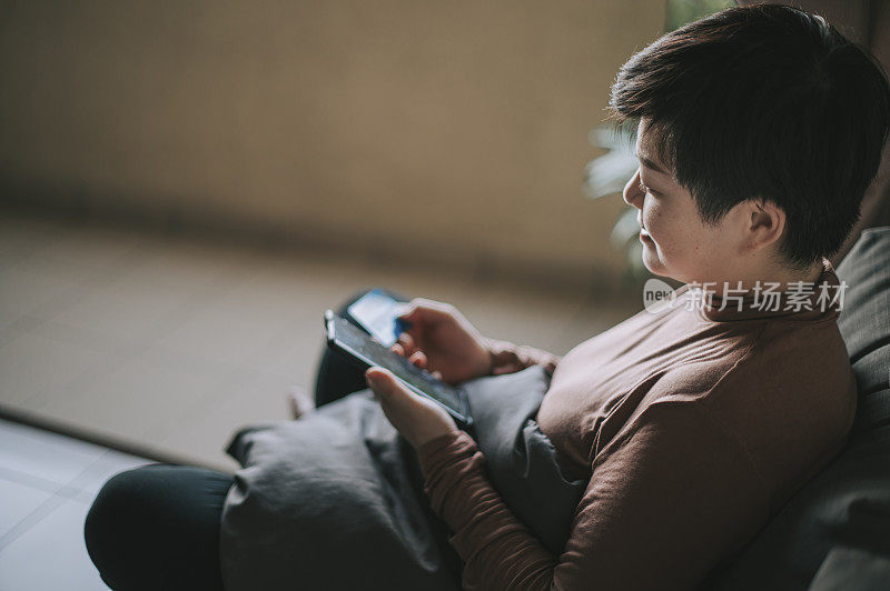 一位亚洲华人中年妇女用她的手机和信用卡在网上购物