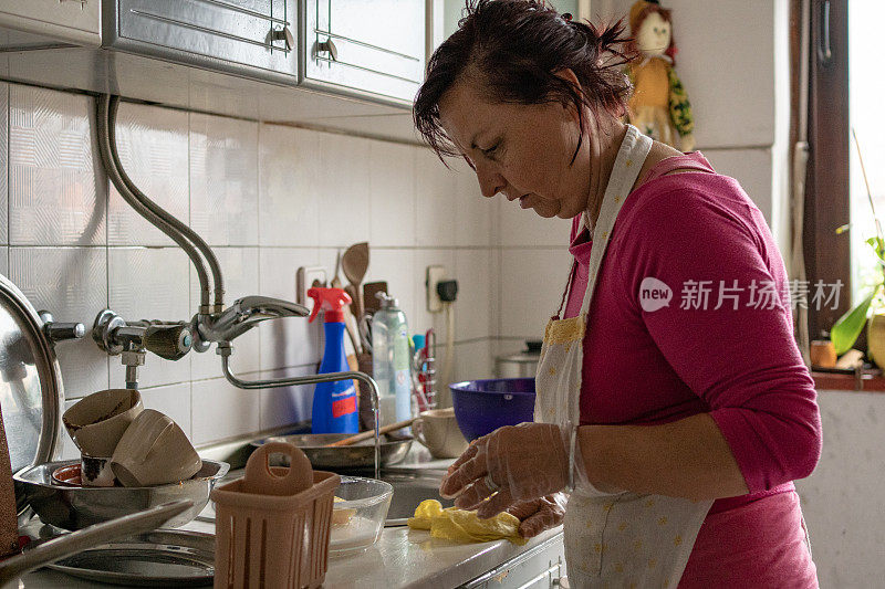 勤劳的女人在她的家庭厨房里洗盘子