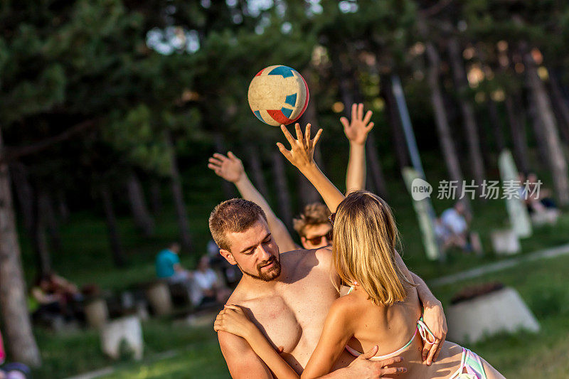快乐的年轻朋友们白天在沙滩上打排球