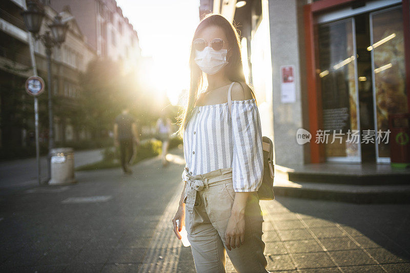 为预防冠状病毒和防雾霾，年轻妇女戴着口罩上街的肖像