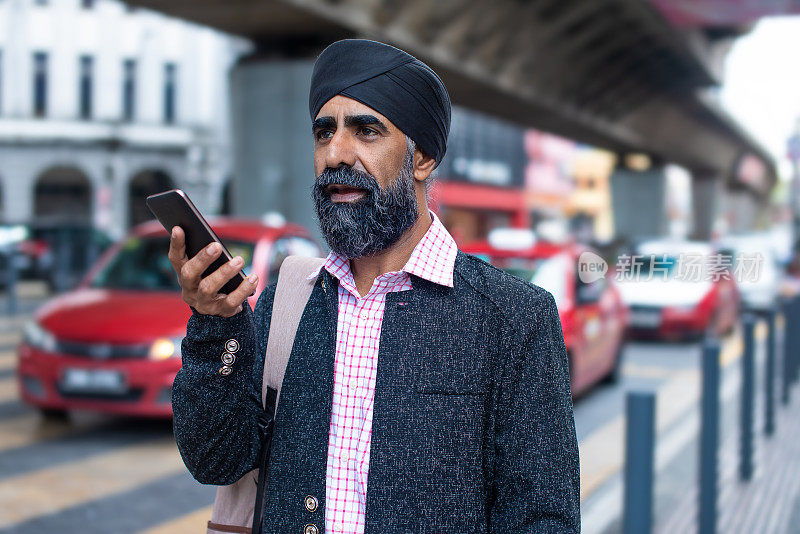 锡克教商人在街上使用智能手机