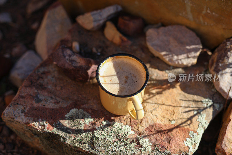 一块岩石上的珐琅咖啡杯的特写图像