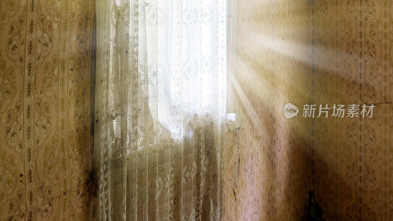 明亮的阳光透过木窗上的透明窗帘照射在古老的空房间里