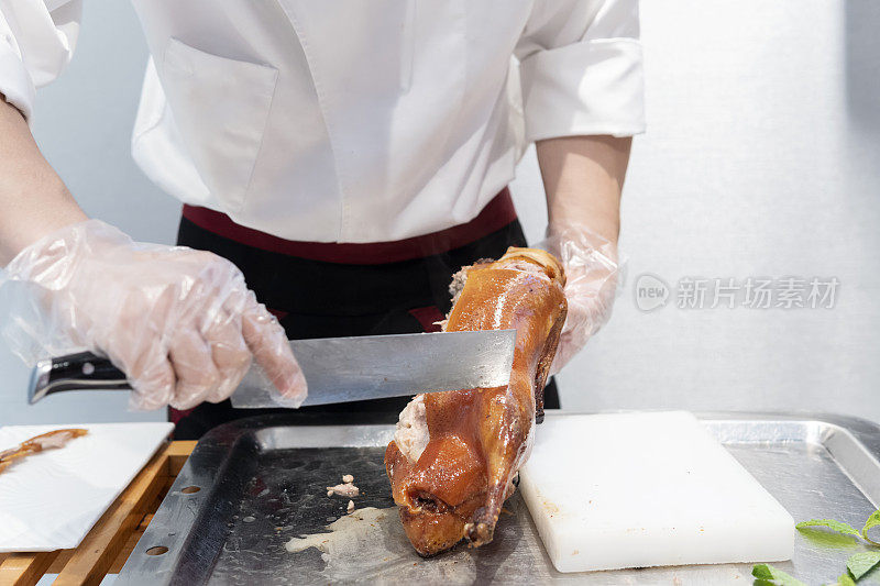 一位厨师在一家餐馆的厨房里切着美味的北京烤鸭