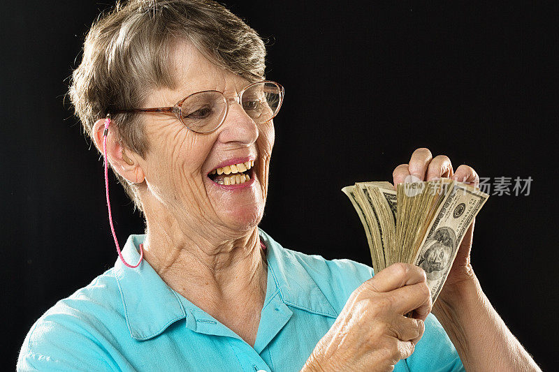 一位70多岁的老妇在数着一叠美元钞票，看起来很开心