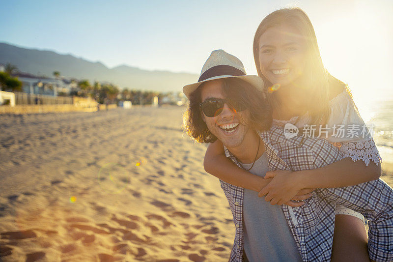 情侣们在日落或日出时在海滩上玩背包游戏