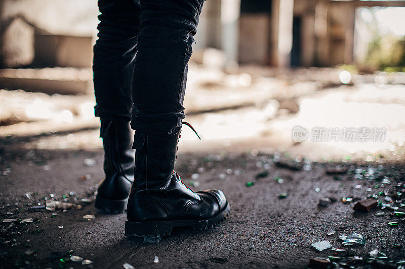 穿着战靴的男人站在废弃的建筑里