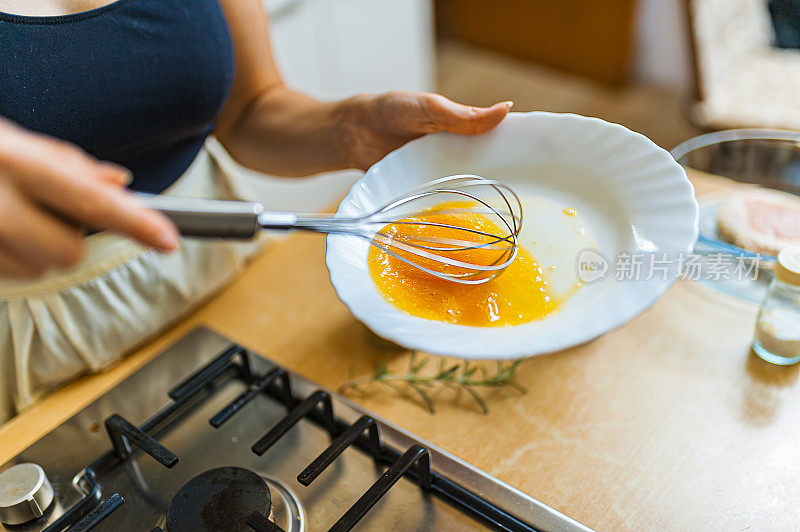 一个女人正在用丝棒搅拌蛋黄。