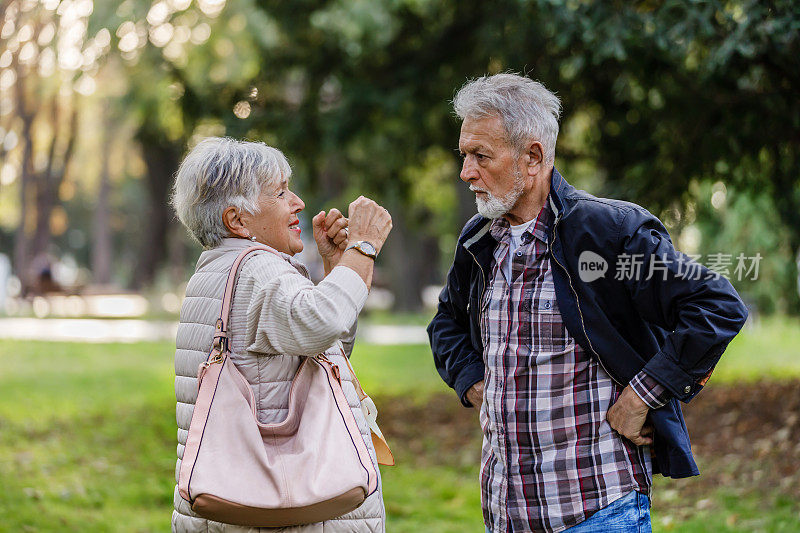 一位老人和他的妻子在一个公园里进行严肃的讨论。