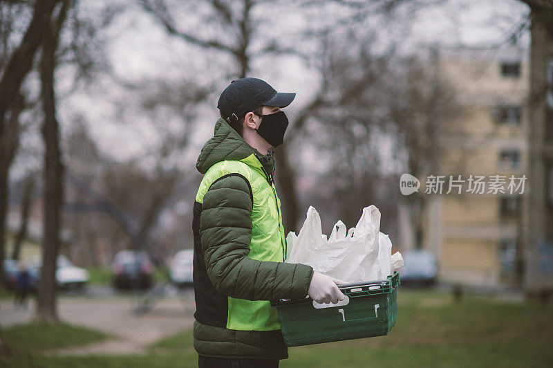 年轻的送货员戴着防护面具和防护手套