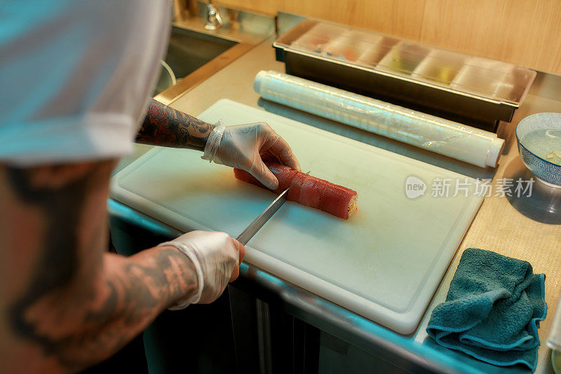 厨师用刀在板上切金枪鱼寿司卷